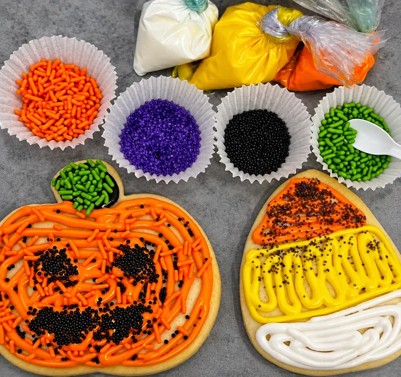 Finished jack-o'-lantern and candy corn sugar cookies covered in icing and sprinkles