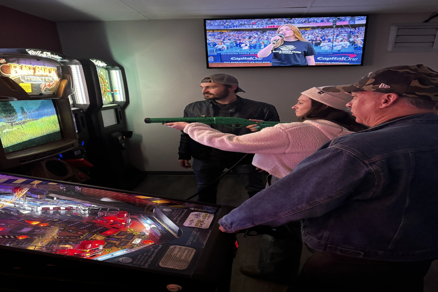 Guests taking aim at a light-gun arcade game beside the pinball machines in the game room