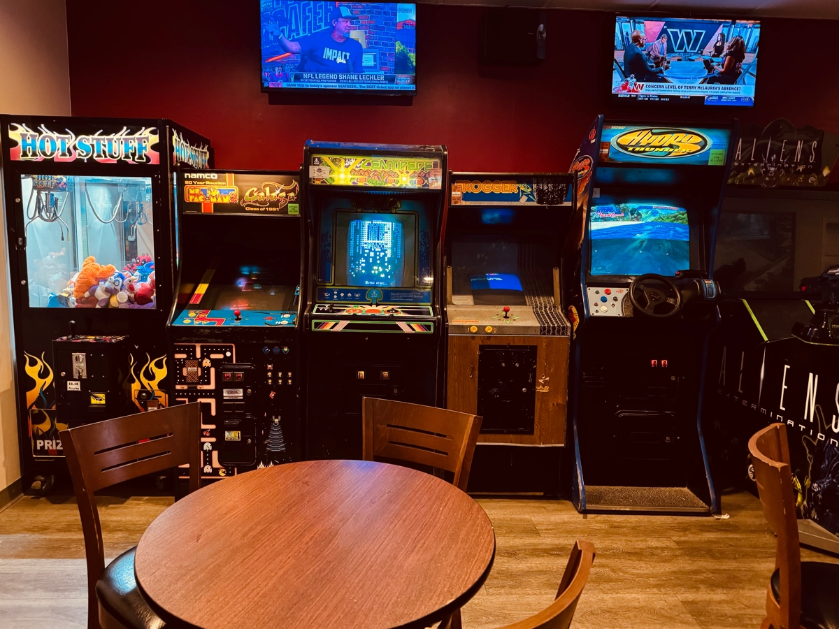 Vintage arcade cabinets and a claw machine in the game room at Cookie Dough Creations