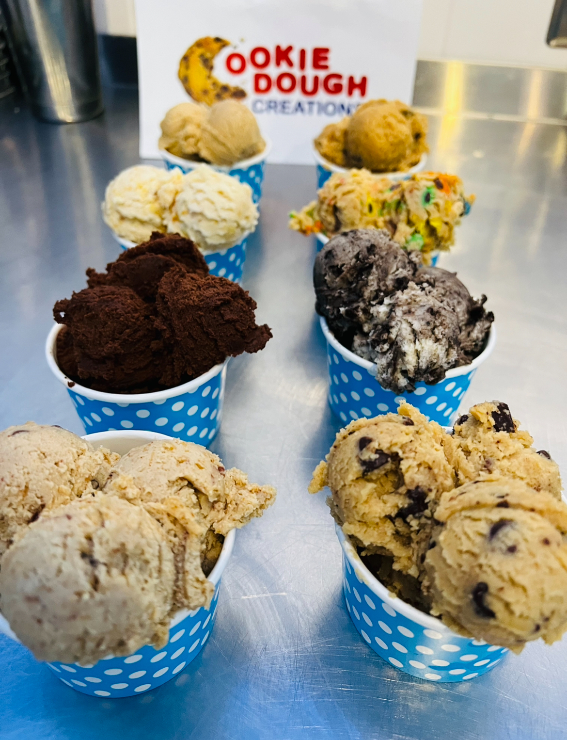 Cups of edible cookie dough flavors lined up on the counter at Cookie Dough Creations
