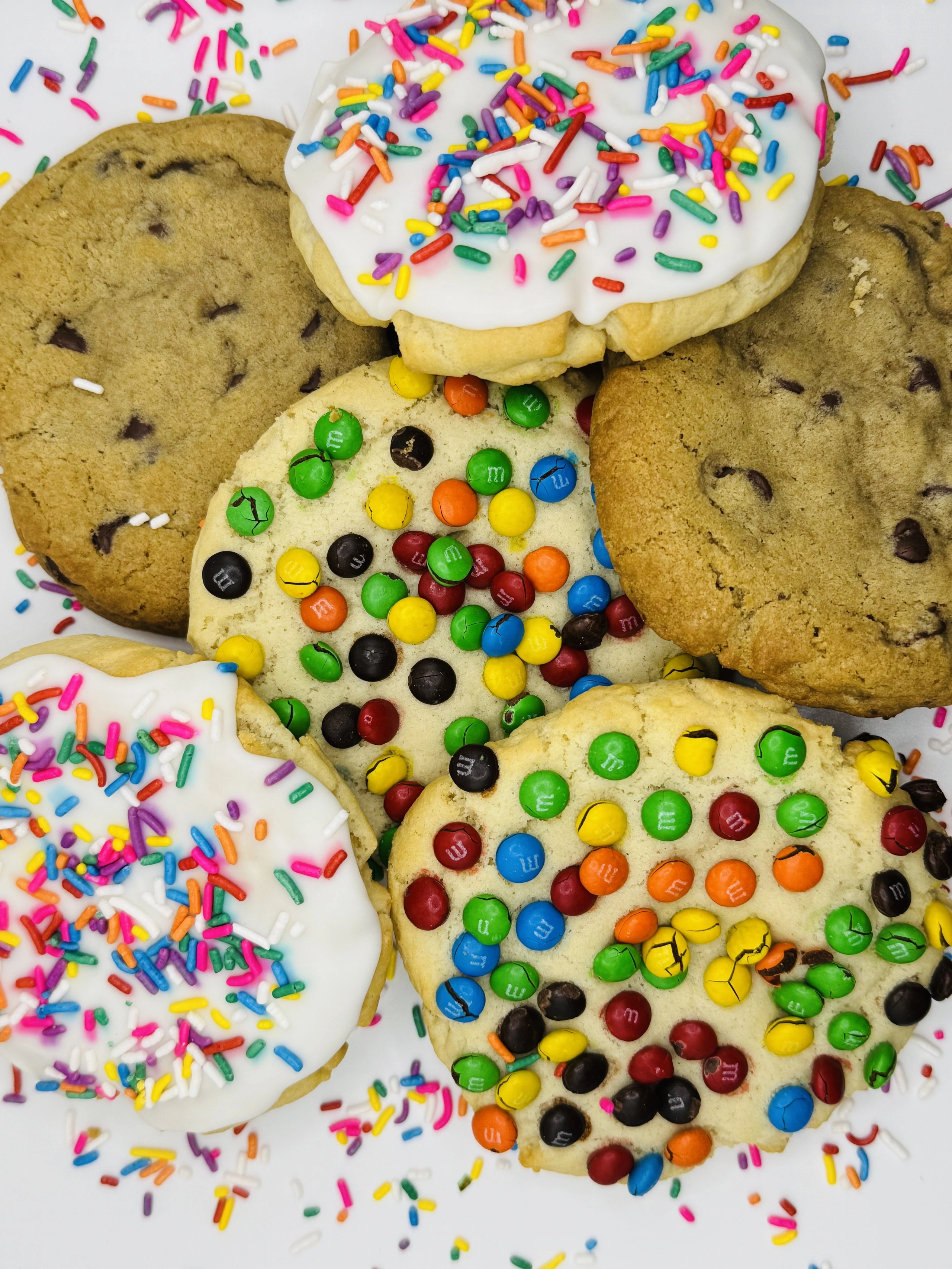 Fresh-baked chocolate chip, M&M and frosted sprinkle cookies scattered with sprinkles