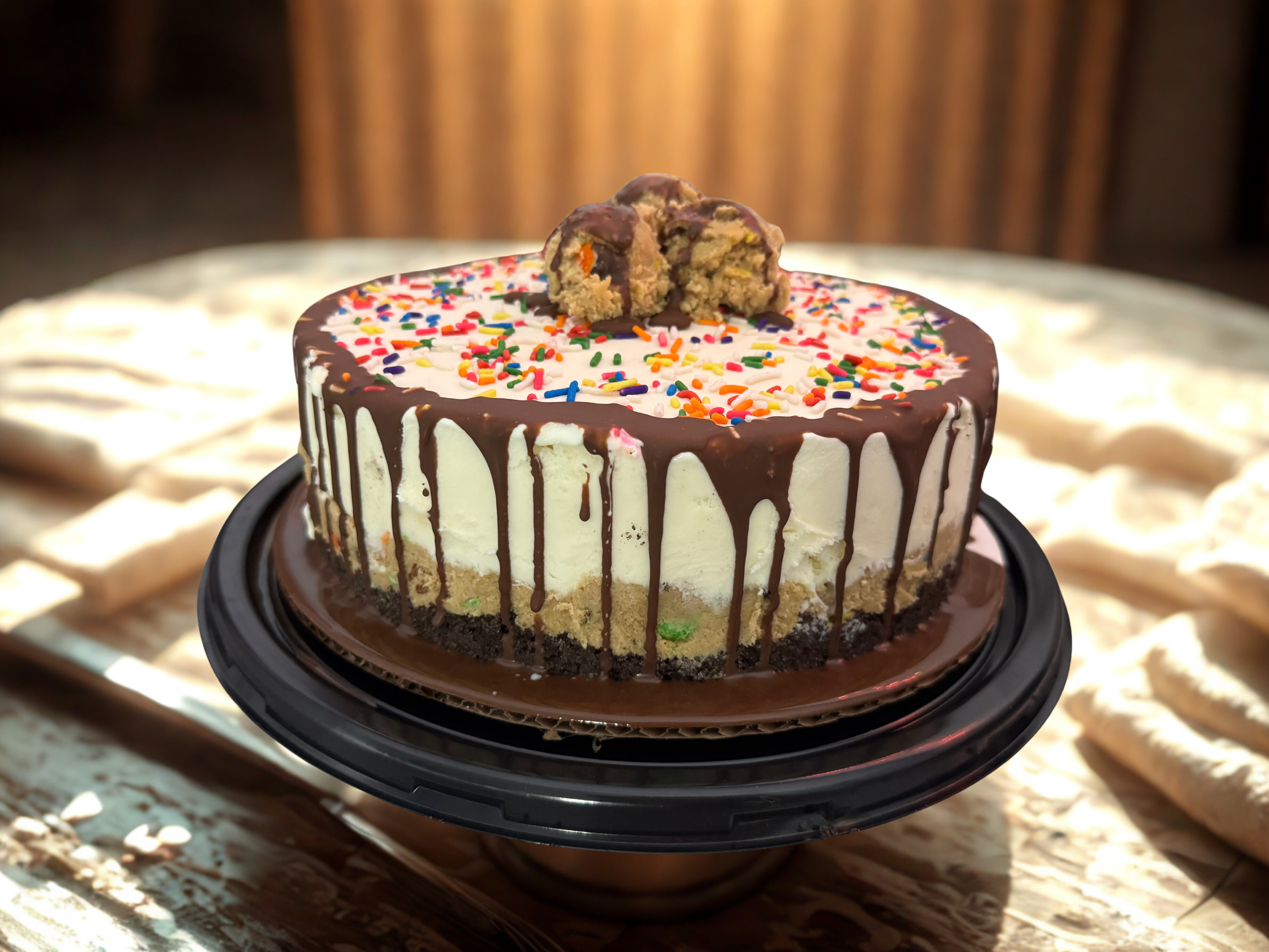 Ice cream cookie dough cake with rainbow sprinkles, chocolate drizzle, and cookie dough on top